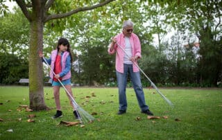 A father and daughter raking leaves